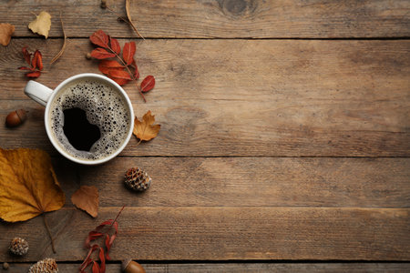 Cup of hot drink and autumn leaves on wooden table, flat lay with space for text. Cozy atmosphereの写真素材