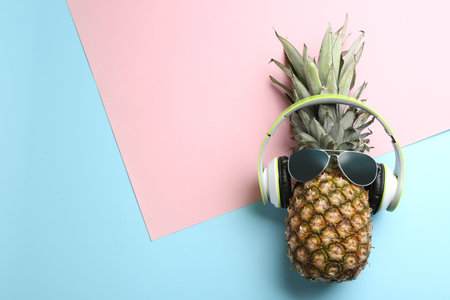 Top view of pineapple with headphones and sunglasses on color background, space for text. creative conceptの写真素材
