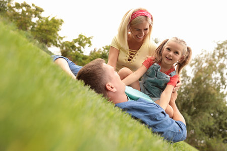 Happy family spending time together in park on green grassの写真素材