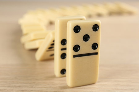 White domino tiles falling on wooden table, closeupの写真素材