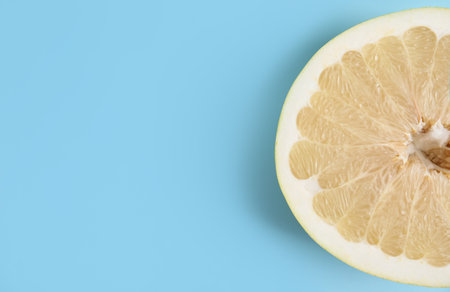Fresh cut pomelo fruit on light blue background, top view. Space for textの写真素材