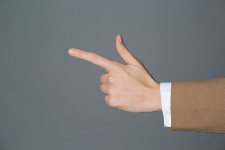 Businesswoman pointing at something on gray background, closeup. finger gestureの写真素材