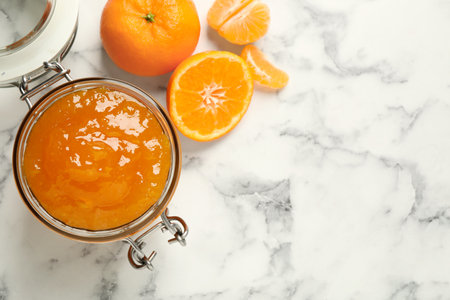 Flat lay composition with tasty tangerine jam on white marble table. Space for textの写真素材
