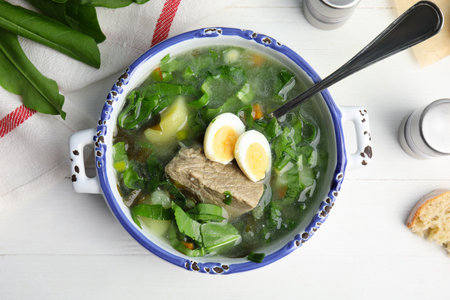 Delicious sorrel soup with meat and eggs served on white wooden table, flat layの写真素材