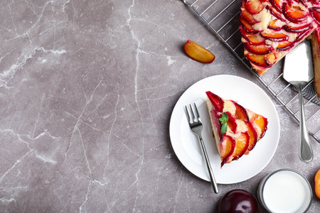 Slice of delicious cake with plums on gray marble table, flat lay. Space for textの写真素材