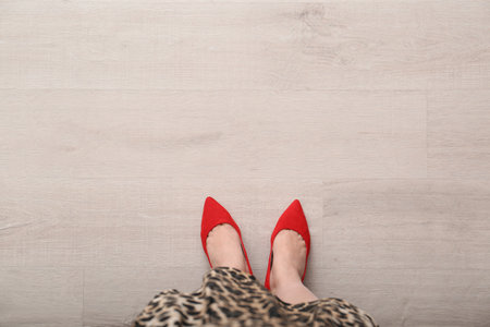 Woman in red shoes standing on wooden floor, top view. Space for textの写真素材