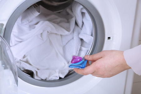 Woman putting laundry detergent capsule into washing machine, closeupの写真素材