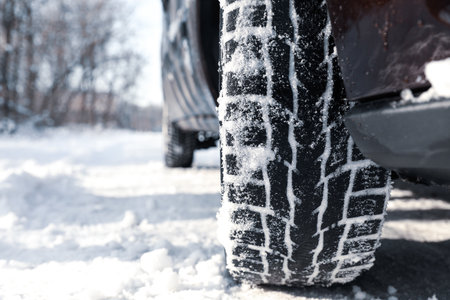 Car with winter tires on snowy road, closeup view. Space for textの写真素材