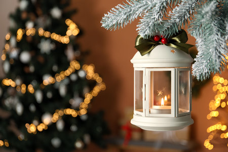 Vintage Christmas lantern with burning candle hanging on fir branch against blurred background. Space for textの写真素材
