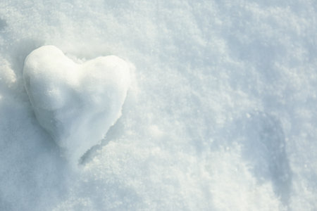 Heart shaped snowball on snow, top view. Space for textの写真素材