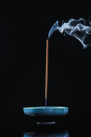 Incense stick smoldering in holder on black backgroundの写真素材