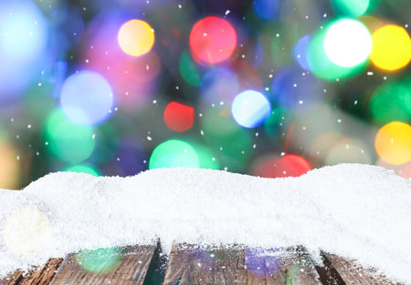 Wooden surface with heap of snow and blurred Christmas lights on background, bokeh effectの写真素材