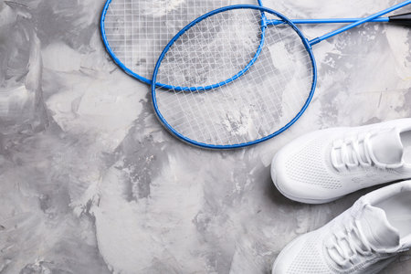 Badminton rackets and shoes on white marble table, flat lay. Space for textの写真素材