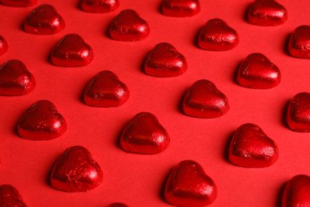 Tasty chocolate heart shaped candies on red backgroundの写真素材