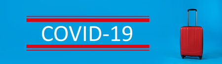 Coronavirus pandemic, lockdown measures. Travel suitcase and text COVID-19 on blue background, banner designの写真素材