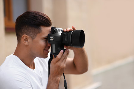 Photographer taking picture with professional camera on city streetの写真素材