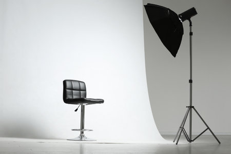 Modern chair and professional lighting equipment in photo studioの写真素材