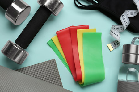 Flat lay composition with fitness elastic bands on light blue background