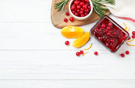 Flat lay composition with cranberry sauce and orange on white wooden table, space for textの写真素材