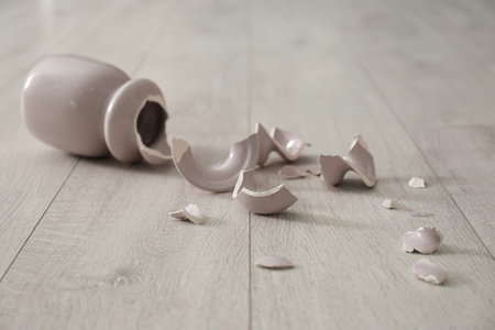 Broken pink ceramic vase on wooden floorの写真素材