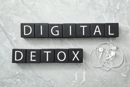 Black cubes with words DIGITAL DETOX and earphones on light gray marble background, flat layの写真素材