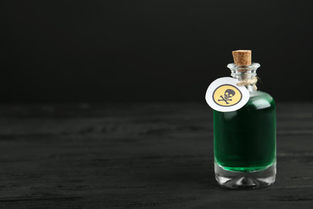 Glass bottle of poison with warning sign on black wooden table. Space for textの写真素材