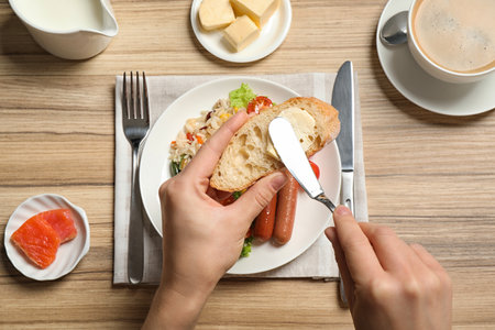 Woman spreading butter on toast at table, top view. buffet serviceの写真素材