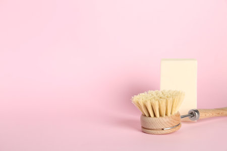 Cleaning brush and soap bar on pink background, space for text. Dish washing suppliesの写真素材