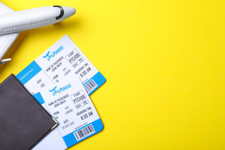 Toy airplane, passport and tickets on yellow background, flat lay with space for text. travel agency conceptの写真素材