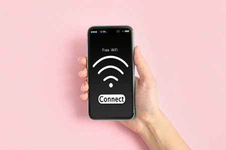 Woman connecting to WiFi using mobile phone on pink background, closeupの写真素材