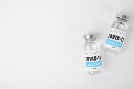 Vials with coronavirus vaccine on white background, flat lay. Space for textの写真素材