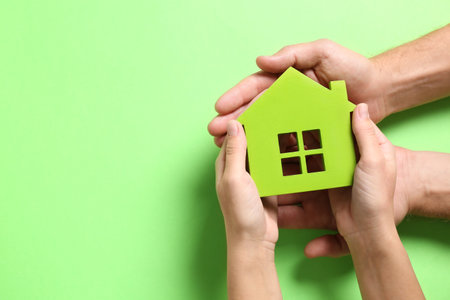 couple holding house model on light green background, top view. Space for textの写真素材