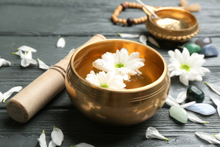 Golden singing bowl with flowers and mallet on gray wooden table, closeup. sound healingの写真素材