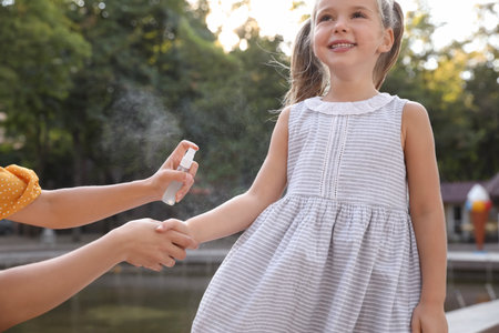 Mother applying insect repellent onto girl's hand outdoors, closeupの写真素材