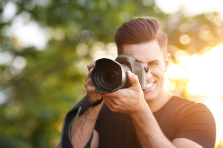 Photographer taking picture with professional camera in countryside, focus on lensの写真素材