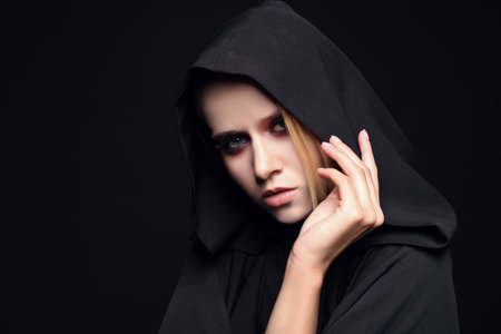 Witch in black mantle on dark background. Scary fantasy characterの写真素材