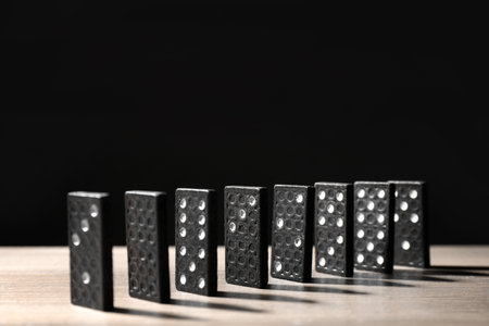 Domino tiles on wooden table against black background. Space for textの写真素材