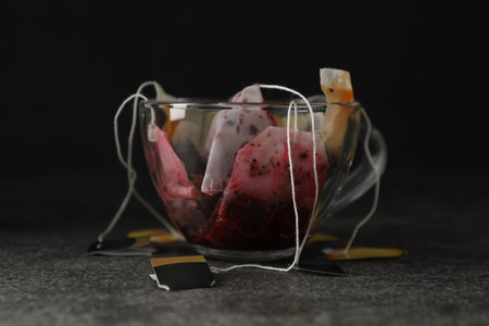 Many used tea bags in glass cup on gray tableの写真素材