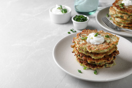 Delicious zucchini fritters served on light table, space for textの写真素材