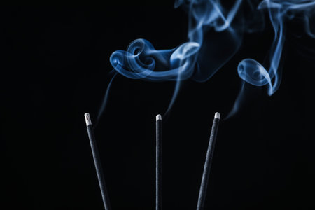 Incense sticks smoldering on black background, closeupの写真素材