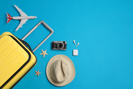 Flat lay composition with suitcase and travel accessories on light blue background, space for text. summer holidaysの写真素材