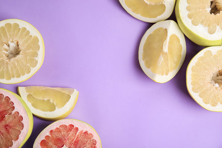 Fresh cut pomelo fruits on lilac background, flat lay. Space for text