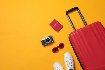 Flat lay composition with suitcase and travel accessories on yellow background, space for text. summer holidaysの写真素材