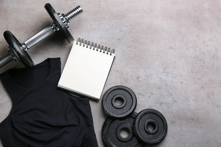 Flat lay composition with sportswear, notebook and equipment on gray background, space for text. Gym workout planの写真素材