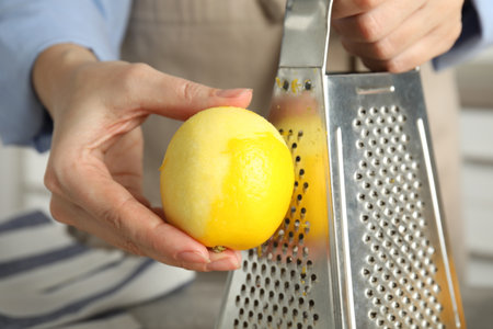 Woman zesting fresh lemon indoors, closeup viewの写真素材