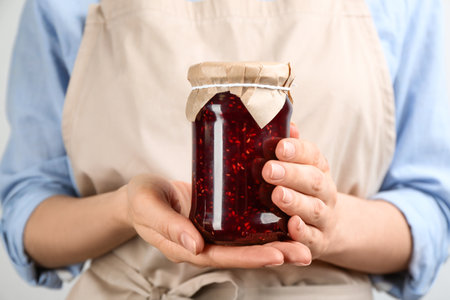 Woman holding glass jar of raspberry jam, closeupの写真素材