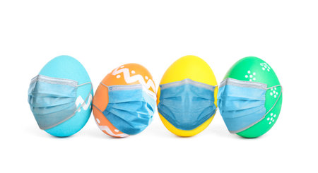 Colorful Easter eggs in protective masks on white backgroundの写真素材