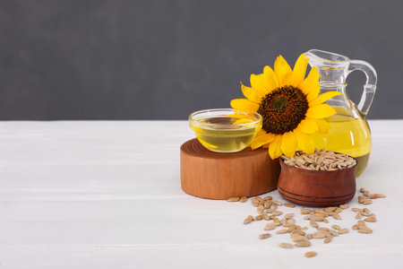 Sunflower, oil and seeds on white wooden table, space for textの写真素材