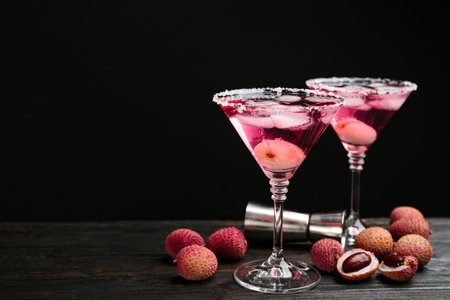 Lychee cocktail on dark wooden table against black background, space for textの写真素材