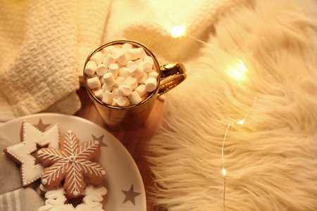 Cup of hot drink with marshmallows, cookies and Christmas lights on table, above viewの写真素材